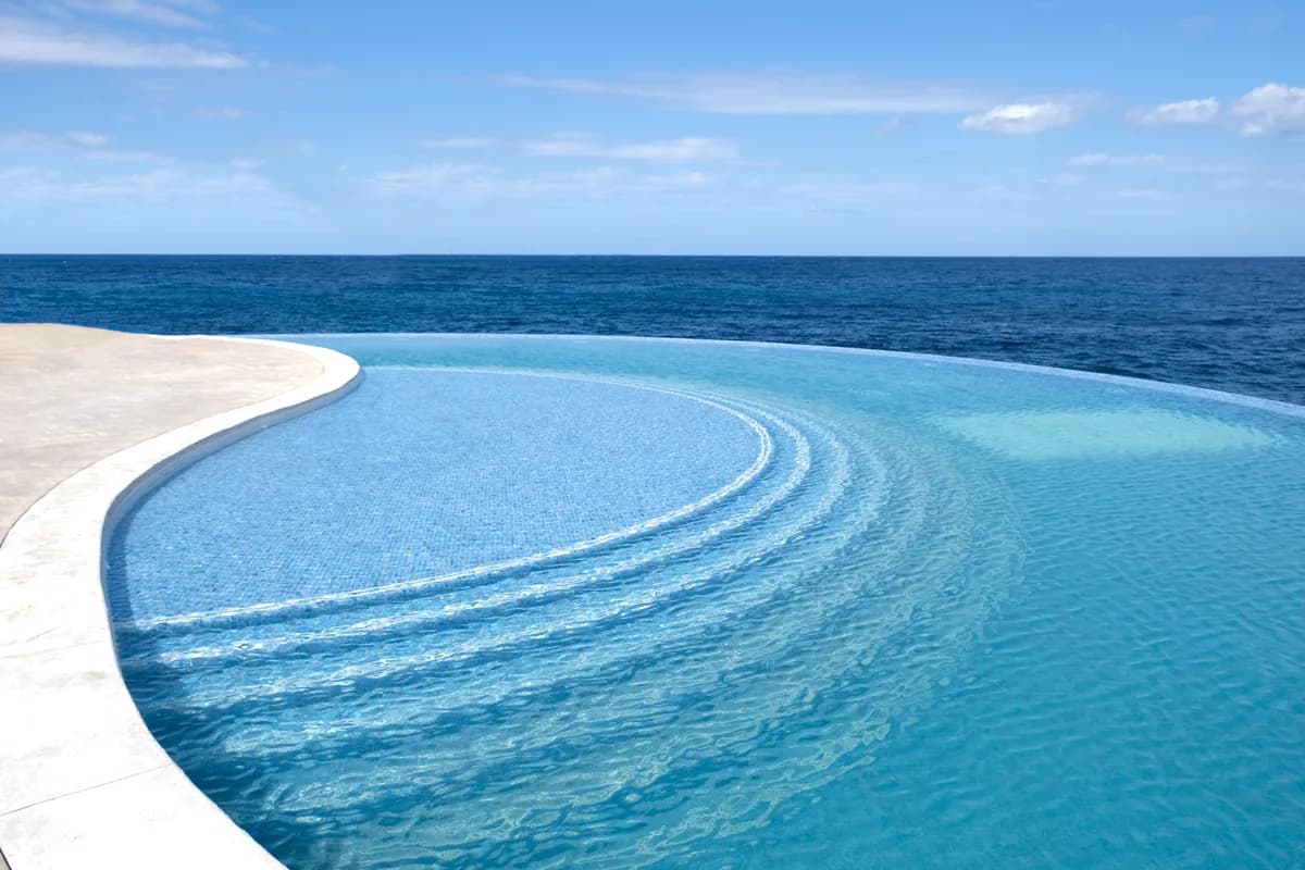 Curved edge of an infinity pool meeting the open ocean